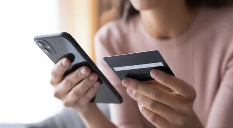 Mulher passando dados do cartão físico para fazer pagamentos e transferências online