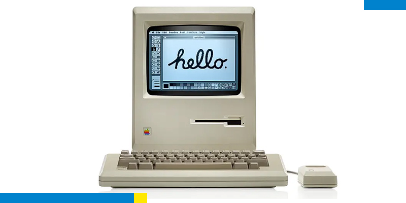 Computador antigo com teclado e mouse e tela escrito "Hello"