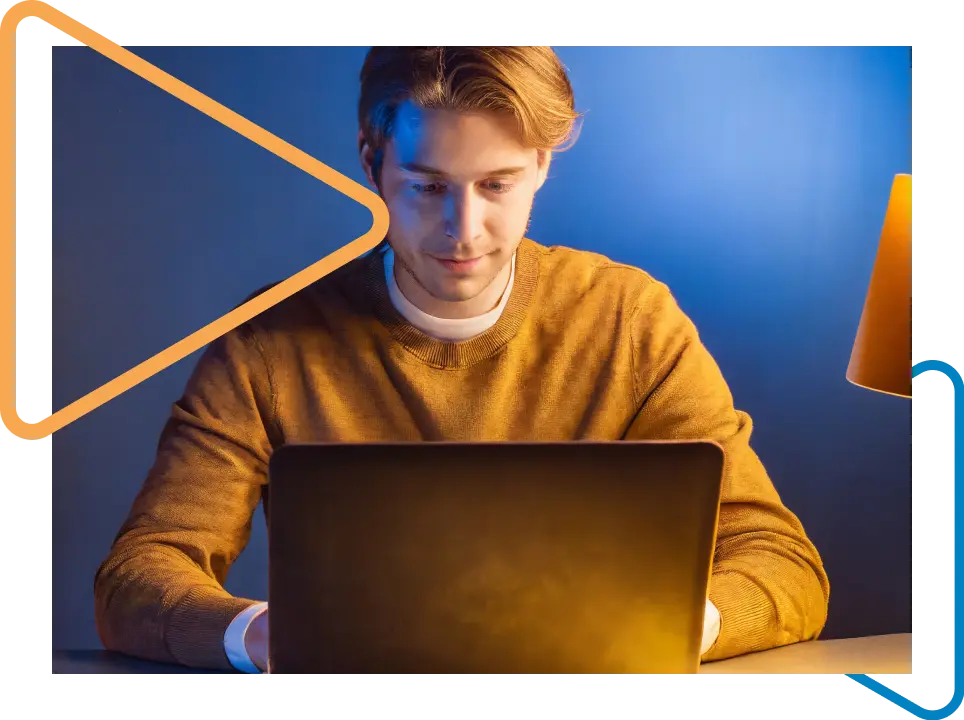 White man in a yellow t-shirt working on a laptop.