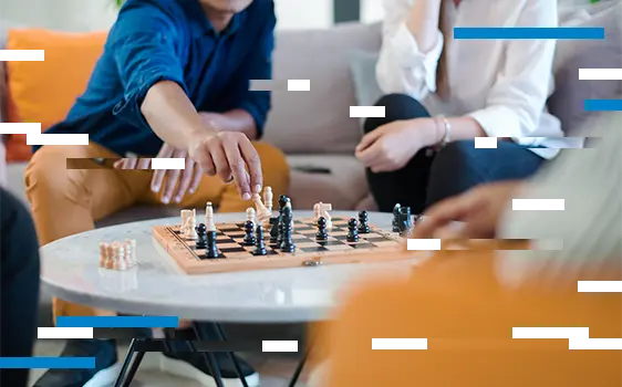 Group of people sitting in a room, playing chess