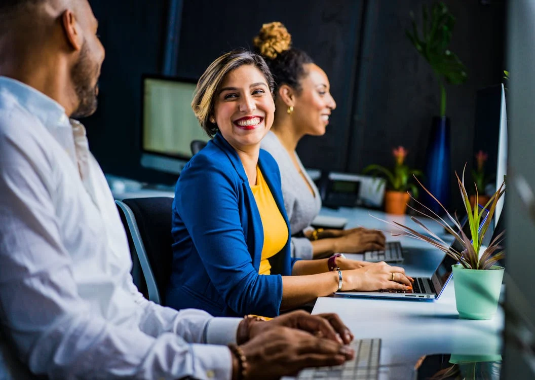 Woman working on her laptop and smiling with her colleagues.