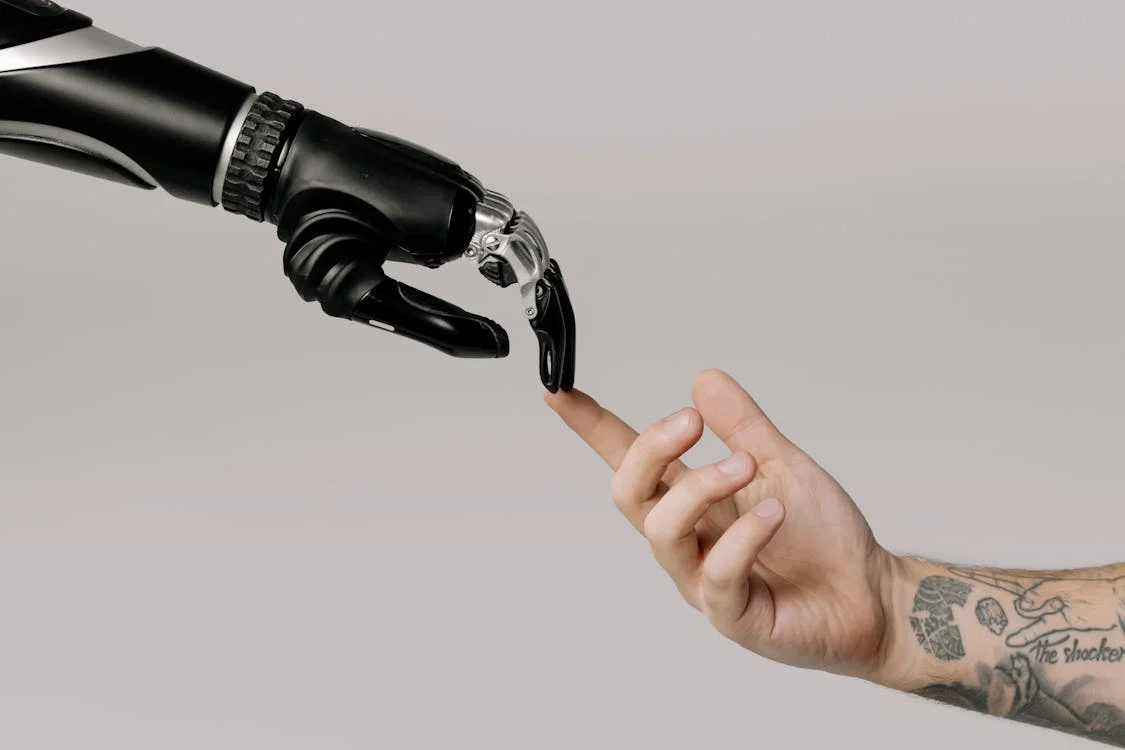 Mão humana e mão robótica se tocando com a ponta dos dedos