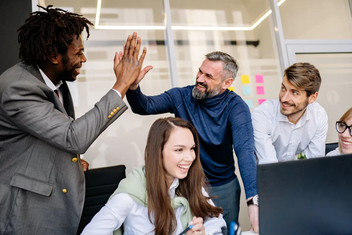 A diverse team working, laughing, and celebrating.