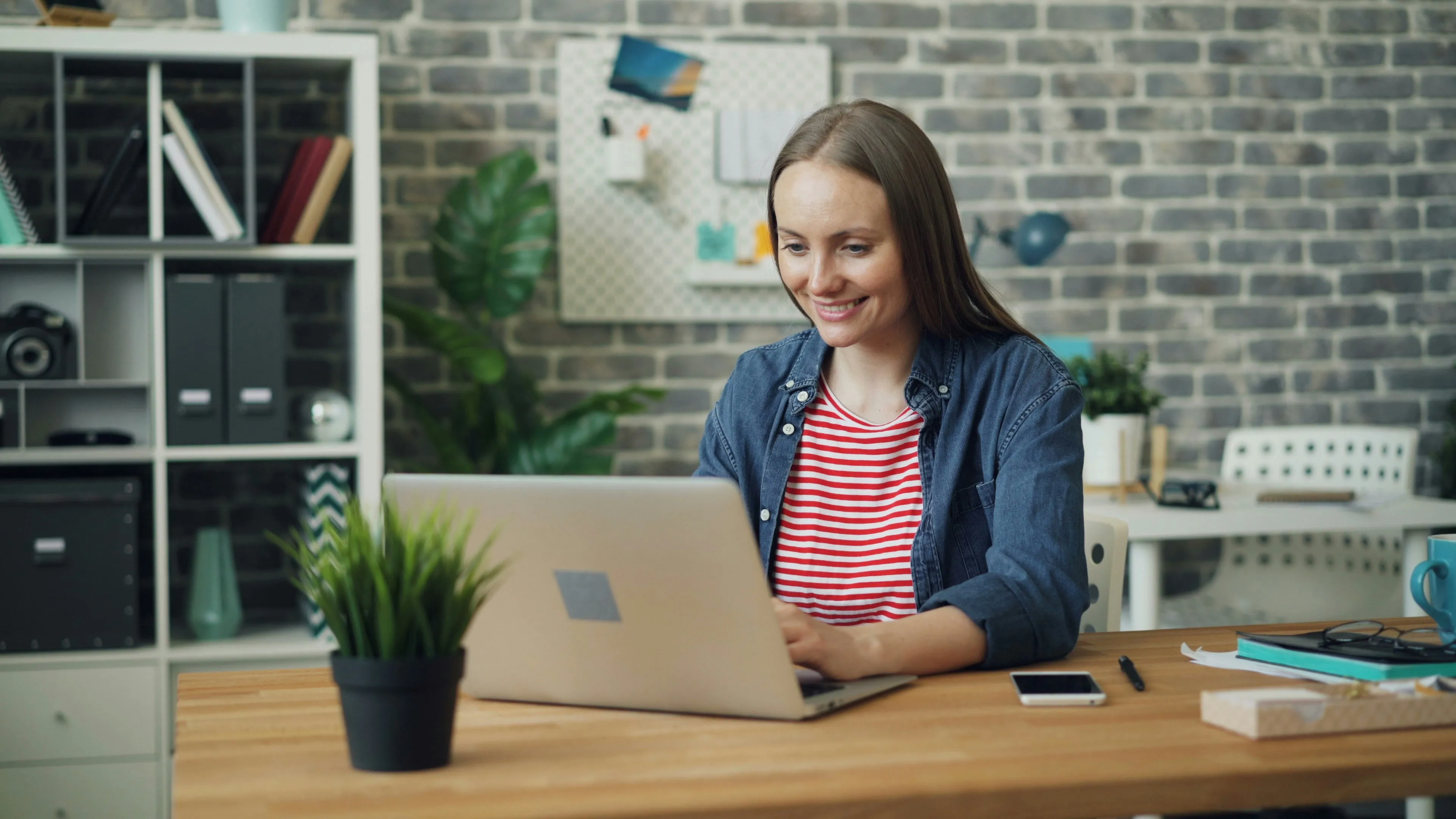 Mulher sorrindo enquanto digita em seu computador.