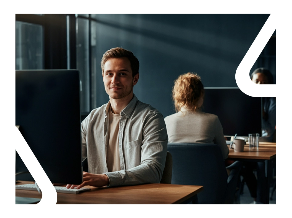 Homem branco trabalhando ao computador e sorrindo.